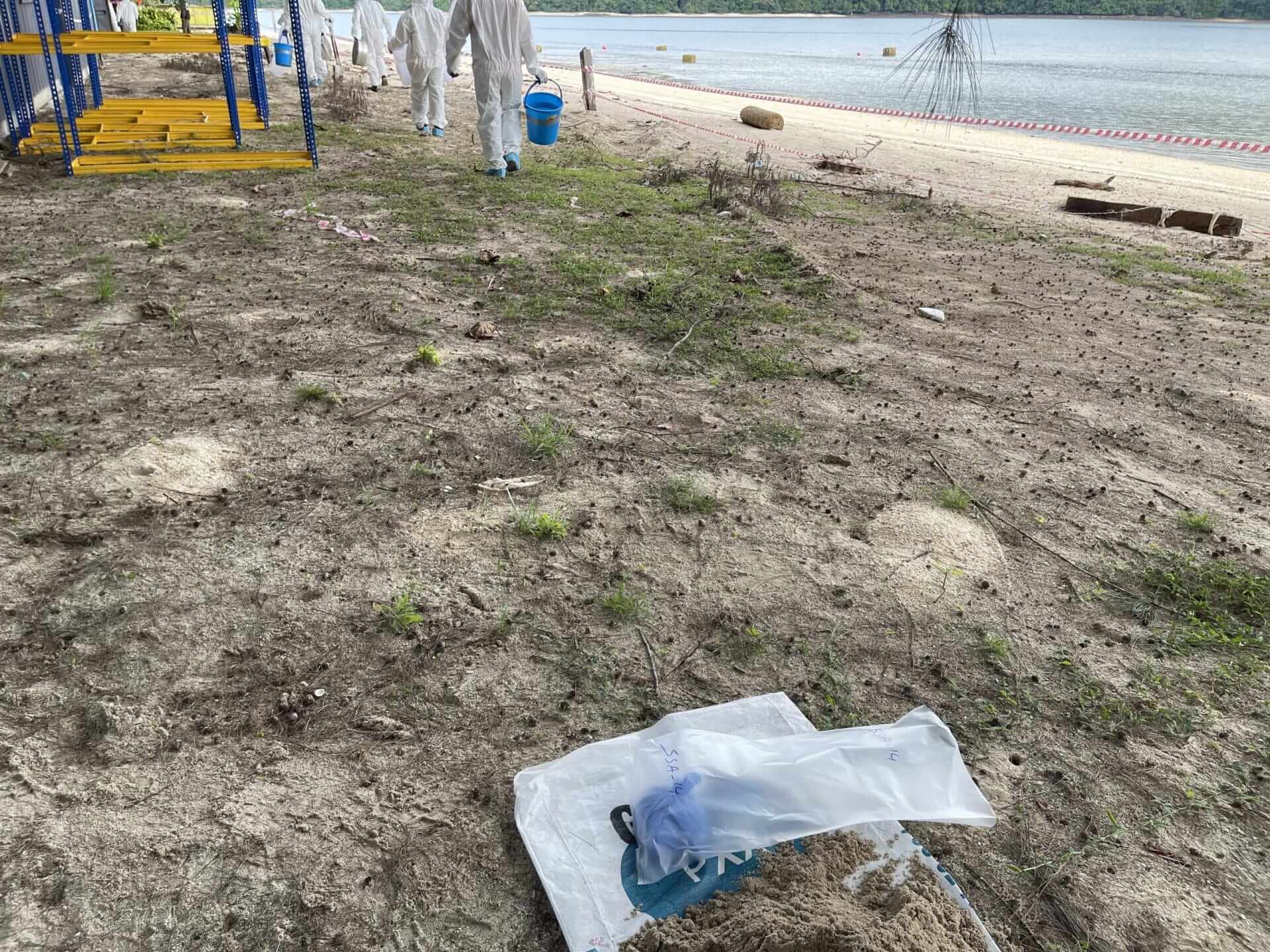 A bag of sand on the beach next to a playground, emphasizing the importance of asbestos awareness training.
